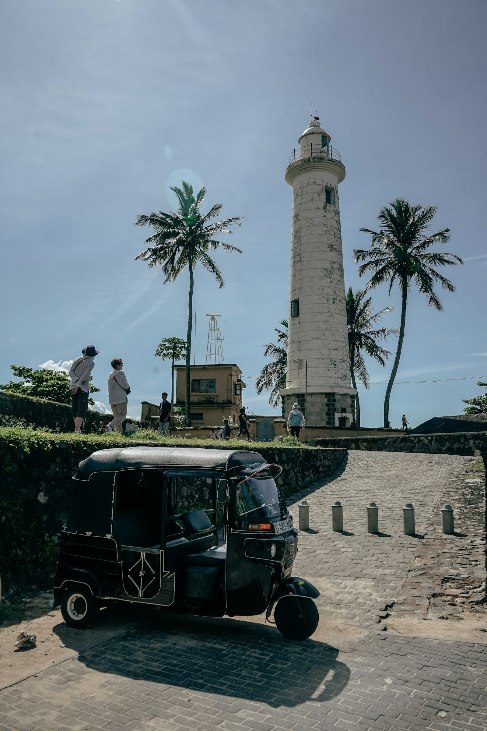 Tuk tuk geparkeerd voor een witte kustvuurtoren in Sri Lanka